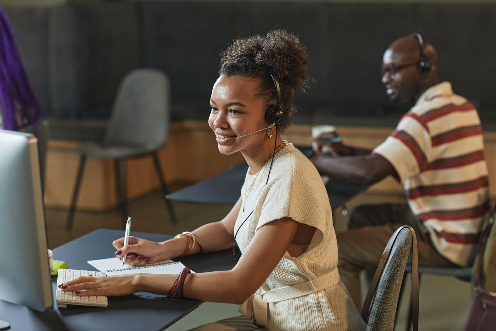 A care coordinator on a headset taking notes at her desk