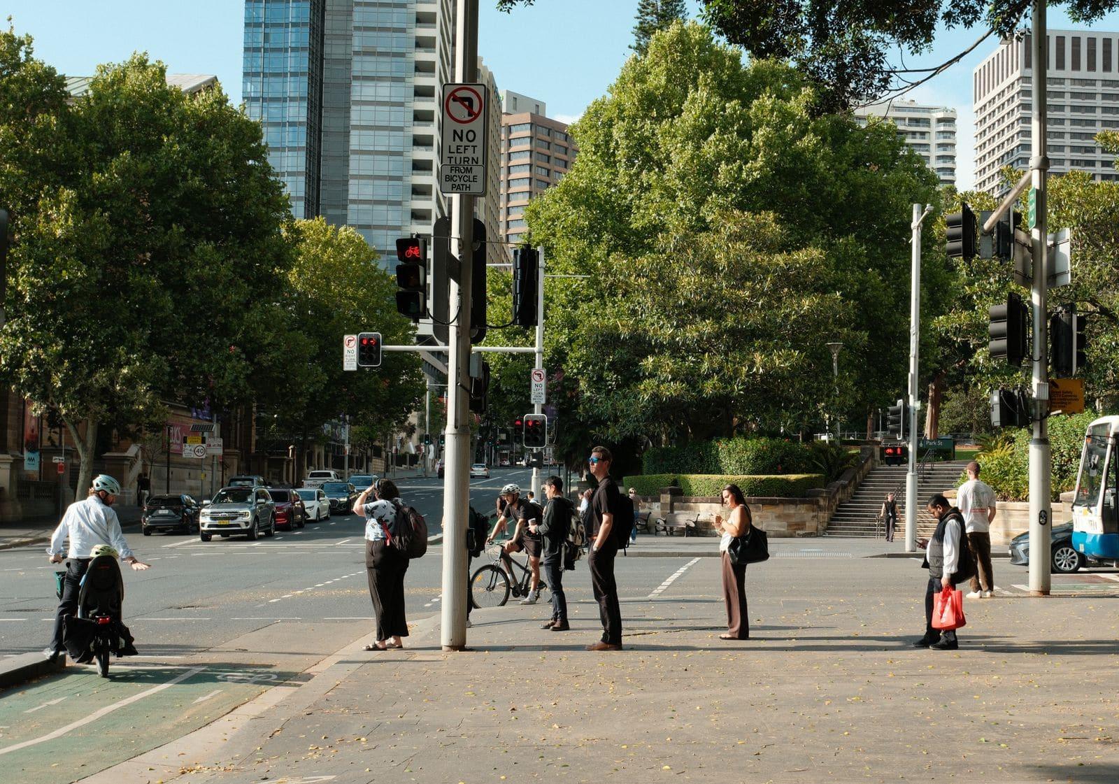 People waiting to cross Park Street beside Hyde Park in the Sydney CBD