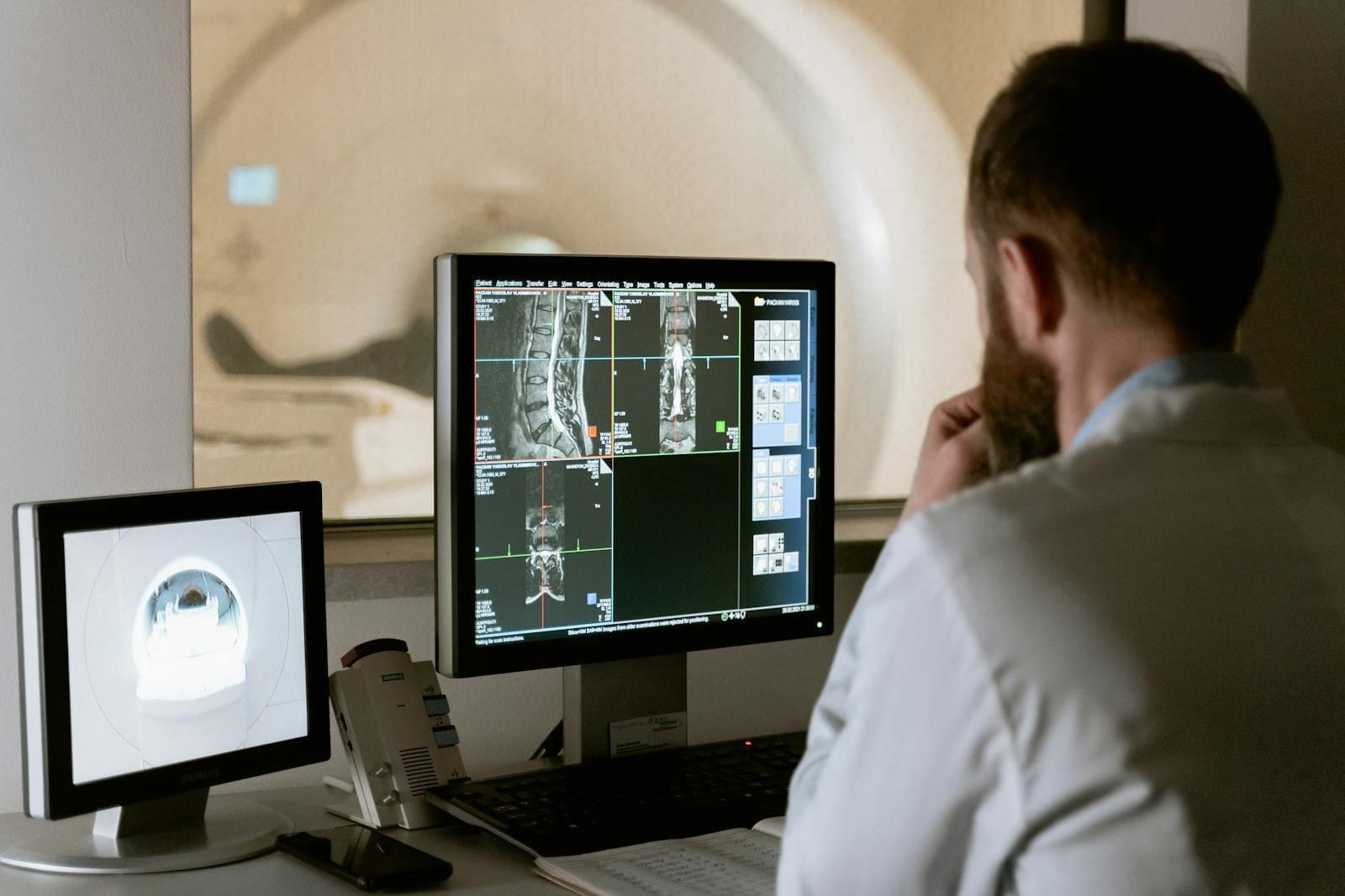 A radiologist reviewing spine MRI images at a workstation