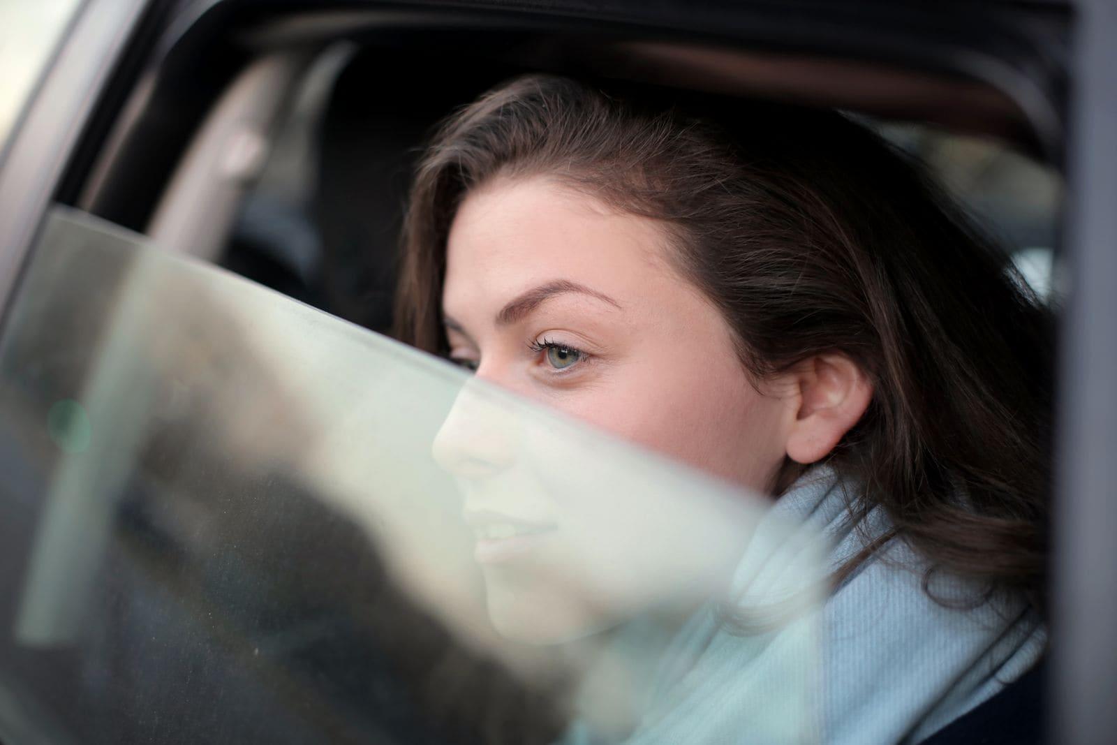 A passenger seen through the side window of a car