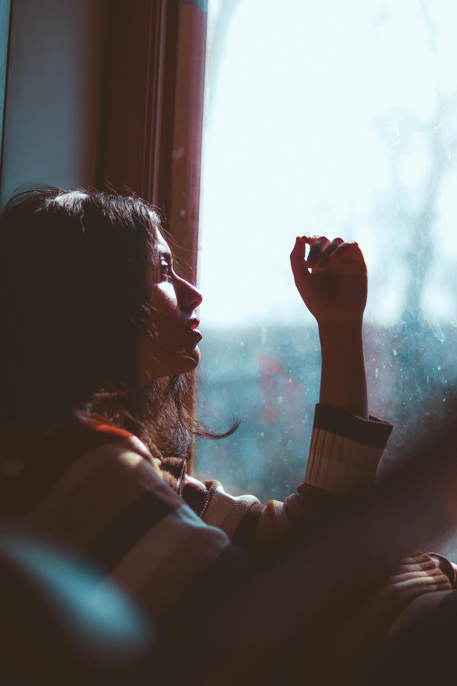 A woman looking out of a window, thinking
